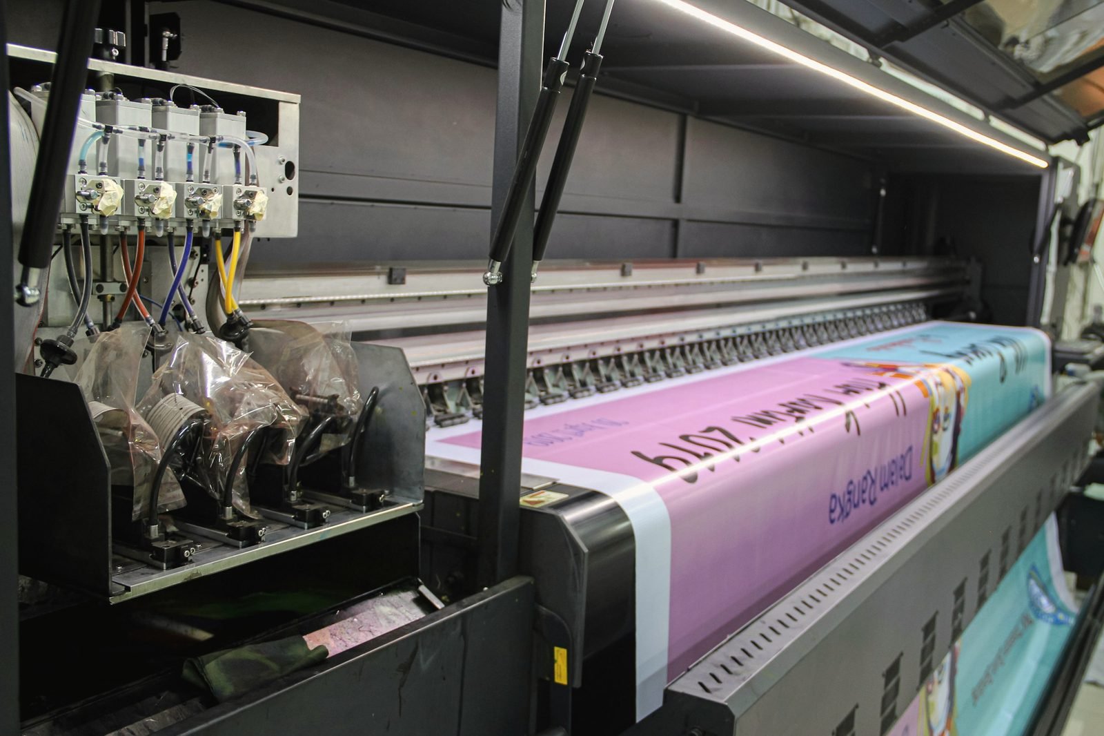 A wide-format printer feeding out a long magenta banner