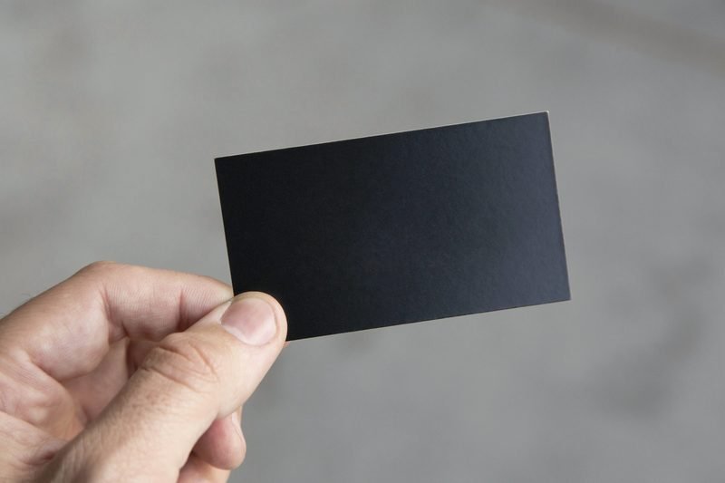A hand holding up a blank black card