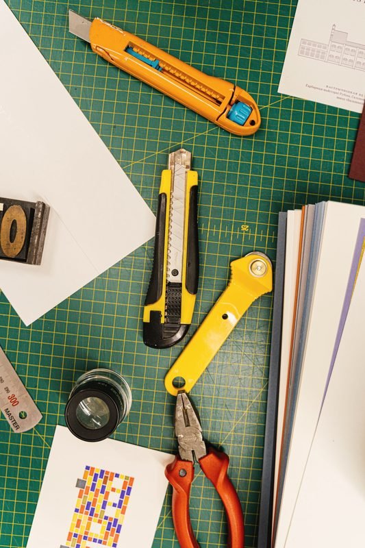 Knives, pliers and paper on a green cutting mat