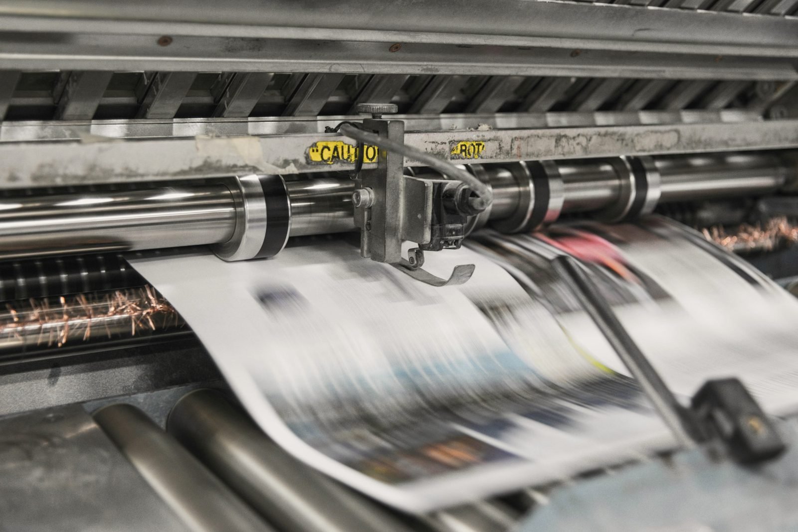 Printed pages running through the rollers of a press