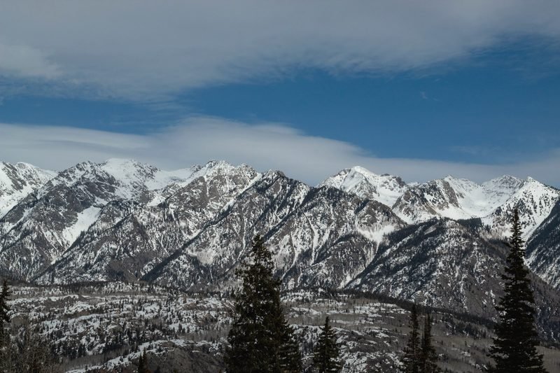 Snow-covered San Juan peaks above a forested valley