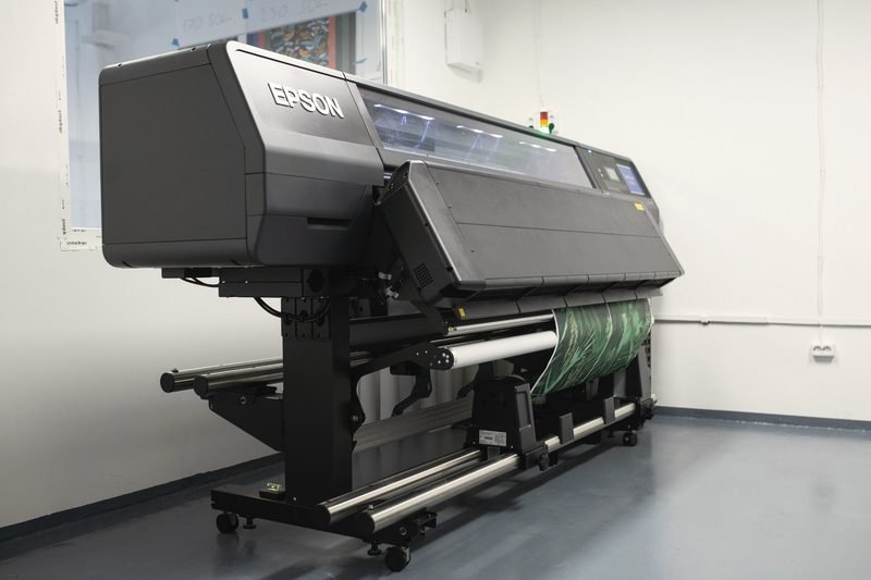 A roll-fed wide-format printer standing in a bright room